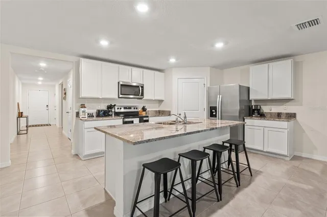 a kitchen with granite countertop white cabinets and stainless steel appliances