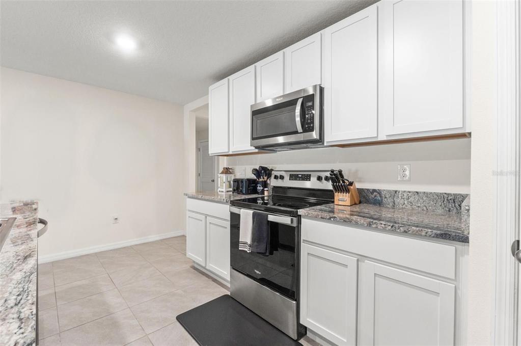 2448 Dothan Avenue Spring Hill, FL 34609 - Photo 7 of 20 a kitchen with stainless steel appliances granite countertop white cabinets a stove a microwave and a sink