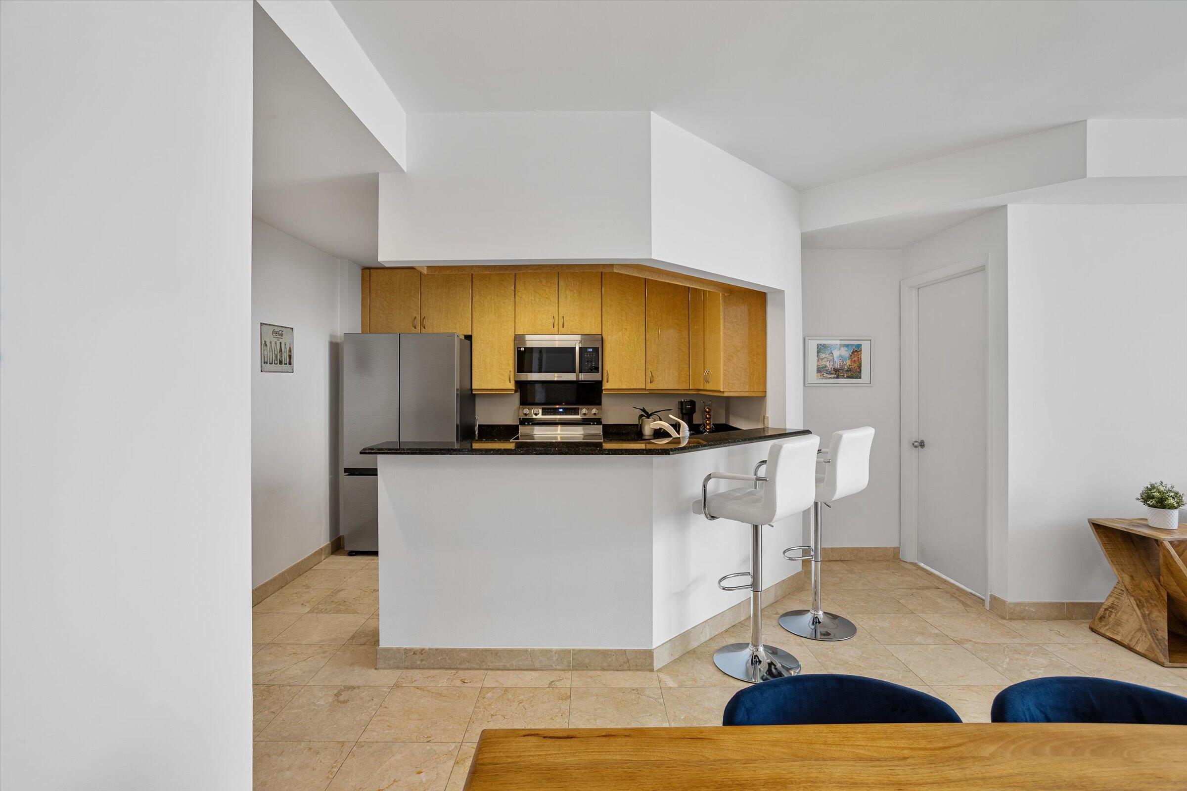 801 Brickell Key Boulevard, Unit 2805 Miami, FL 33131 - Photo 13 of 42 a kitchen with stainless steel appliances kitchen island granite countertop a refrigerator a stove a microwave oven with white cabinets and wooden floor