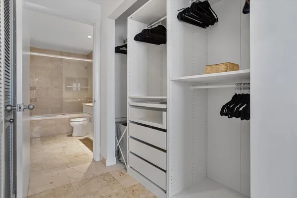 a walk in closet and view of bathroom