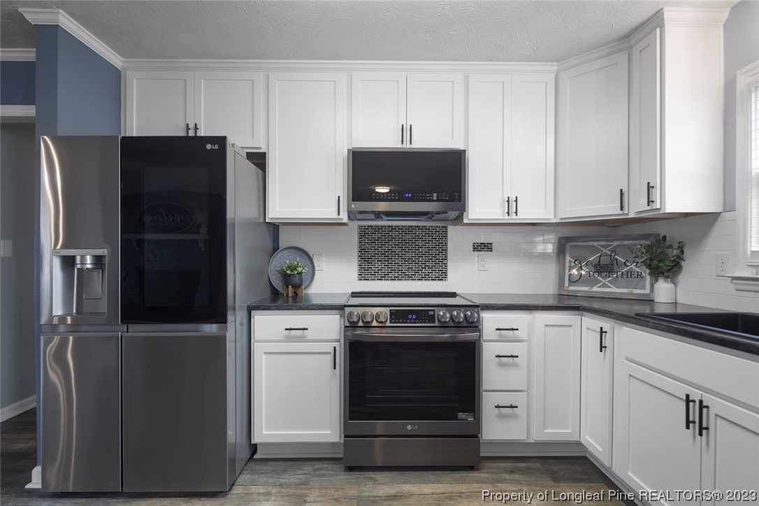 5843 Labonte Drive Hope Mills, NC 28348 - Photo 15 of 43 a kitchen with white cabinets and stainless steel appliances