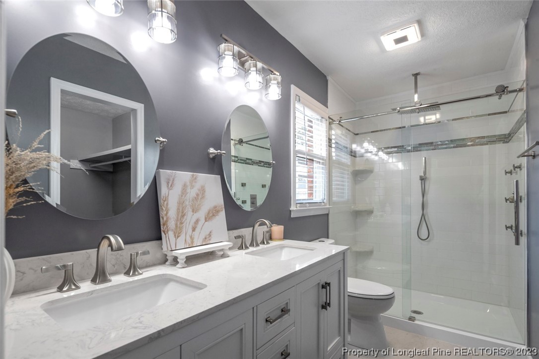 5843 Labonte Drive Hope Mills, NC 28348 - Photo 30 of 43 a bathroom with a double vanity sink toilet mirror and shower