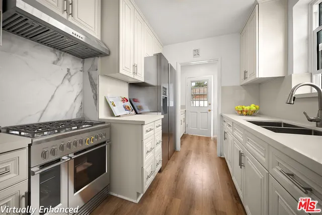 a kitchen with a stove a sink and wooden floor
