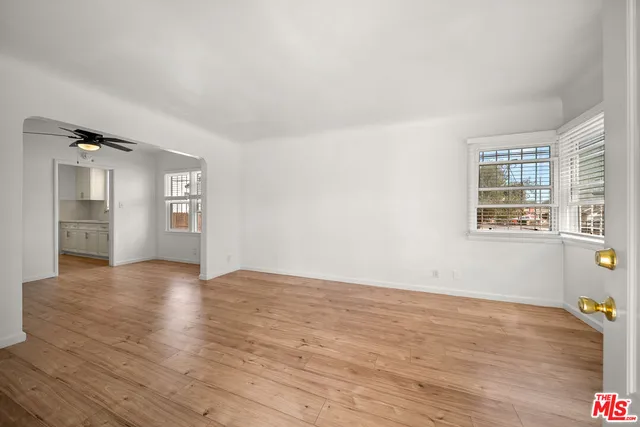 a view of an empty room with window and wooden floor
