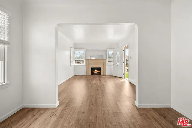 an empty room with wooden floor fireplace and windows