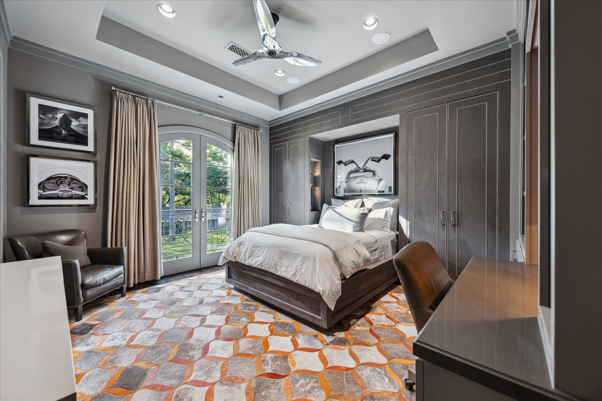 220 Merrie Way Lane Houston, TX 77024 - Photo 42 of 50 This elegant room features designer-upholstered walls with nailhead trim, French doors to a Juliet balcony, built-in shelving with integrated desk, a tray ceiling with recessed lighting, and stained white oak floors.