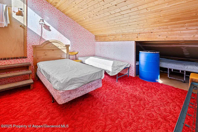 a bedroom with a bed and dresser with wooden floor