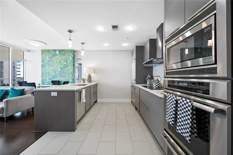 a kitchen with stainless steel appliances a large counter top a stove a chimney a sink and cabinets