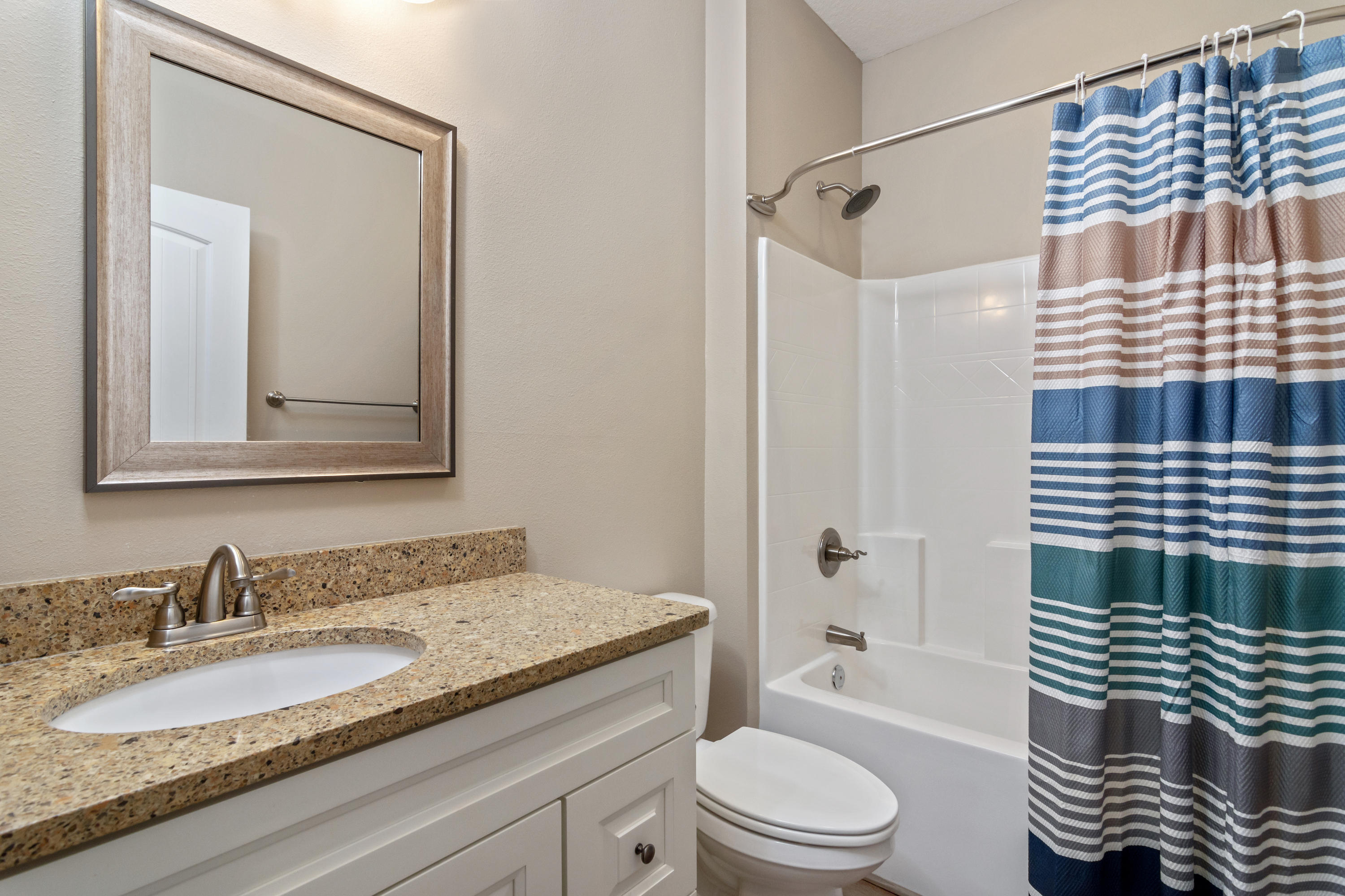 6076 Carina Road Crestview, FL 32539 - Photo 33 of 38 a bathroom with a granite countertop toilet a sink and a mirror