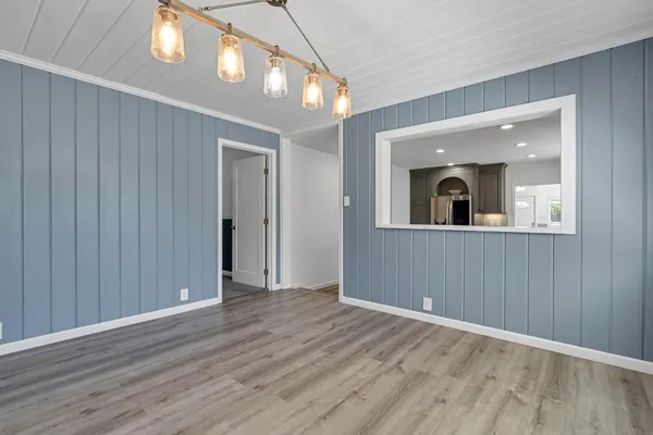a view of an empty room with wooden floor and a mirror