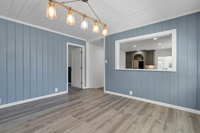 a view of an empty room with wooden floor and a mirror