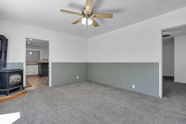 an empty room with a fireplace and a chandelier fan