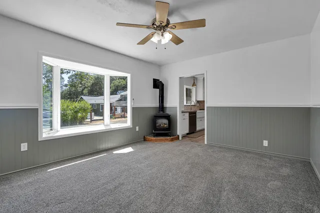 an empty room with windows and ceiling fan