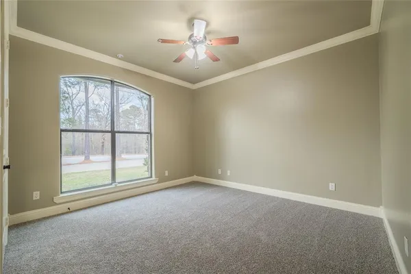 an empty room with chandelier fan and windows