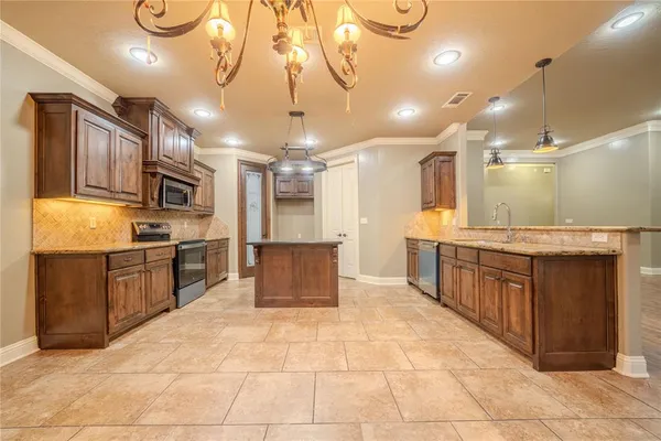 a large kitchen with a large counter top kitchen space a sink stainless steel appliances and cabinets