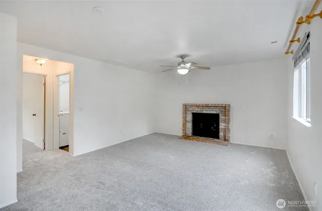 an empty room with windows and fireplace