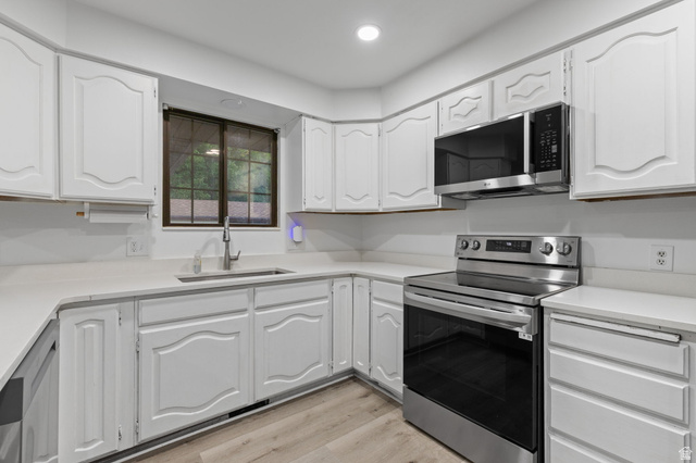 875 Cedar Hollow Road Lehi, UT 84043 - Photo 66 of 76 White cabinetry with decorative paneling, light countertops, stainless steel appliances, and wood-finish flooring