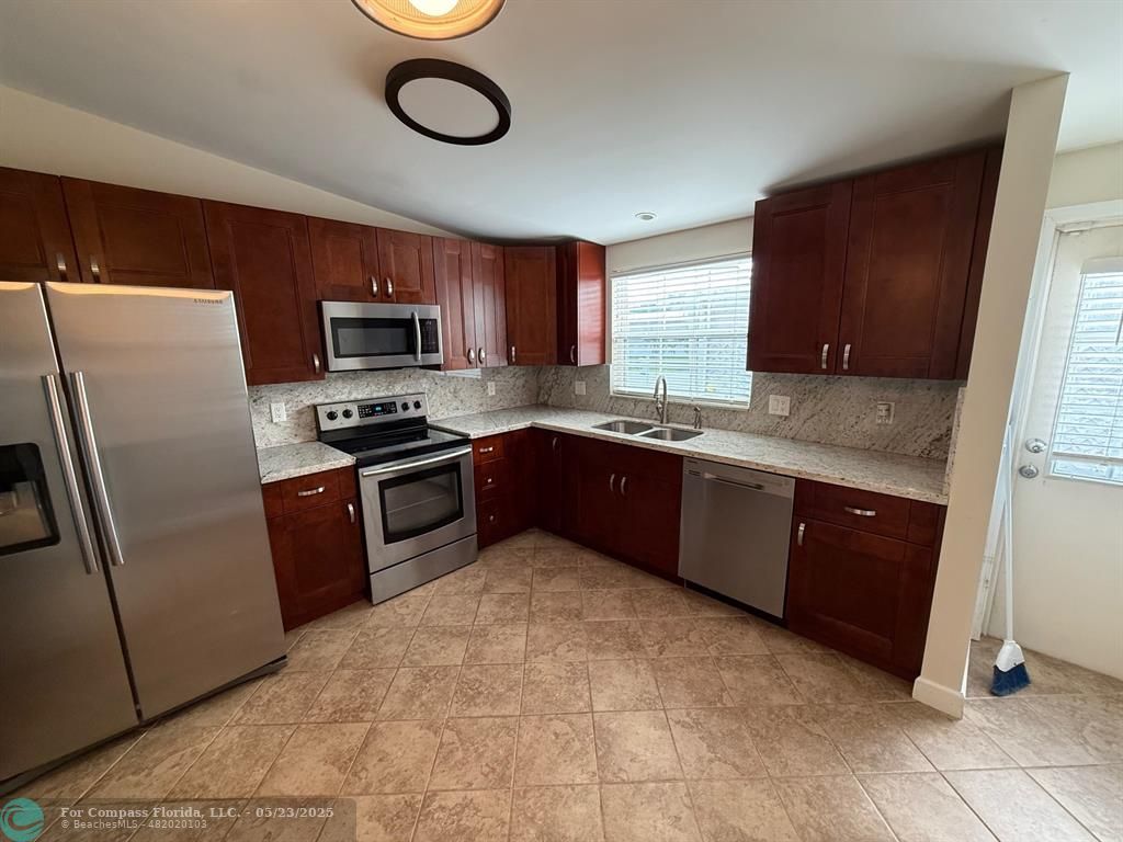 8550 Southwest 23rd Place Davie, FL 33324 - Photo 3 of 9 a kitchen with stainless steel appliances granite countertop a stove a sink dishwasher a refrigerator and a microwave oven with wooden floor