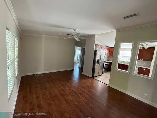 an empty room with wooden floor and a kitchen