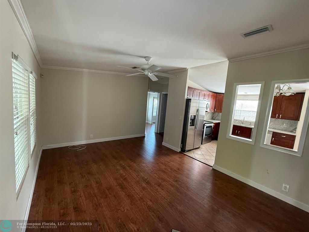 8550 Southwest 23rd Place Davie, FL 33324 - Photo 6 of 9 an empty room with wooden floor and a kitchen