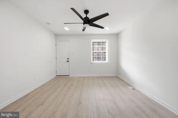 an empty room with ceiling fan and windows