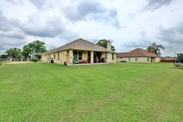 a view of a house with a big yard and large trees