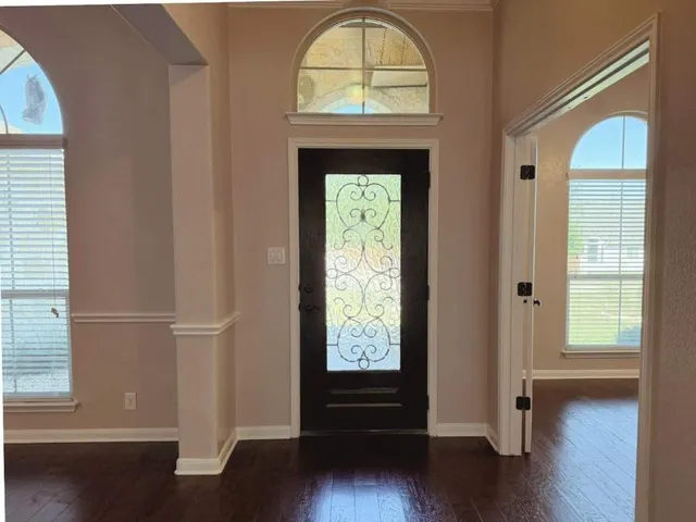 an empty room with wooden floor windows and entryway