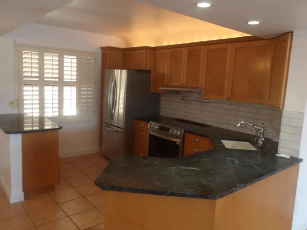 a kitchen with stainless steel appliances granite countertop a refrigerator a stove and a sink