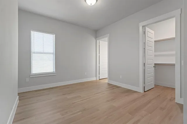 an empty room with wooden floor closet and windows
