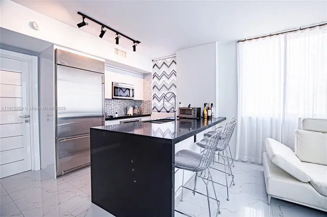 a kitchen with stainless steel appliances granite countertop a sink and a refrigerator
