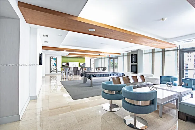 a living room with furniture a flat screen tv and a floor to ceiling window