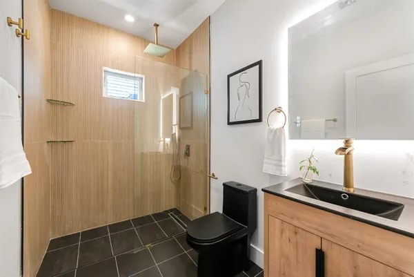 a bathroom with a granite countertop sink a toilet and shower
