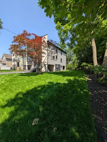 a view of a house with a big yard and large trees