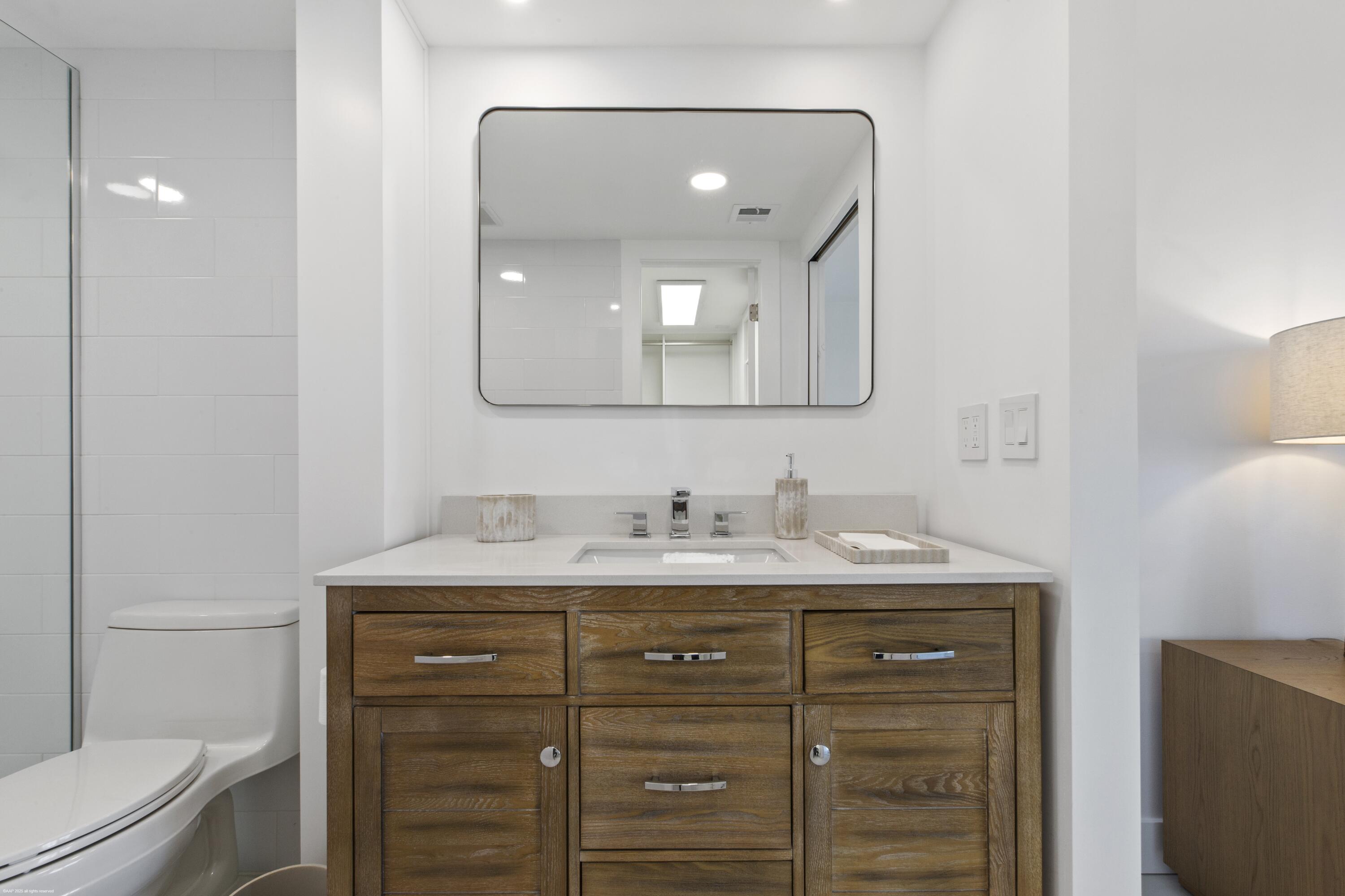 1030 Sugar Sands Boulevard, Unit 267 Singer Island, FL 33404 - Photo 30 of 51 a bathroom with a granite countertop sink vanity mirror and toilet