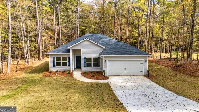 a front view of a house with a yard outdoor seating and covered with trees