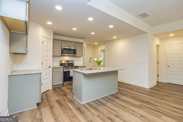 a kitchen with stainless steel appliances granite countertop a sink a stove a refrigerator and a microwave