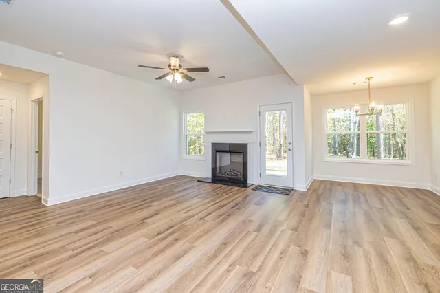 an empty room with wooden floor fireplace and windows