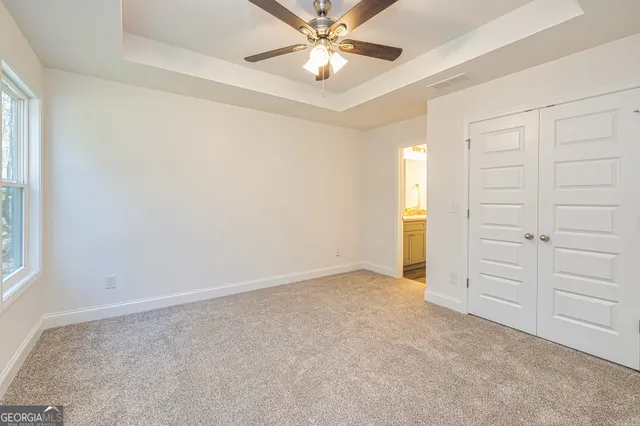 an empty room with closet and a chandelier fan