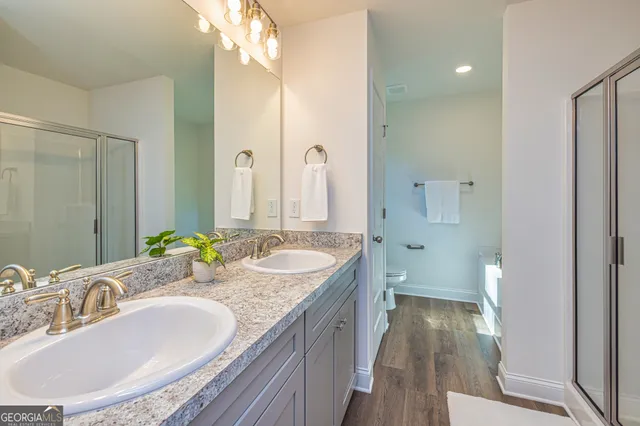 a bathroom with a granite countertop double vanity sink and mirror with shower
