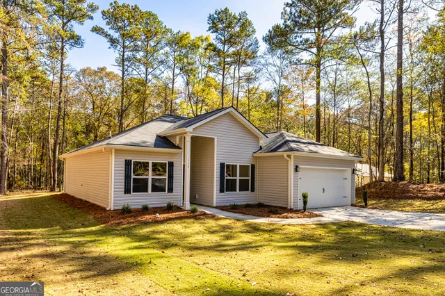 a view of a white house with a yard and large trees