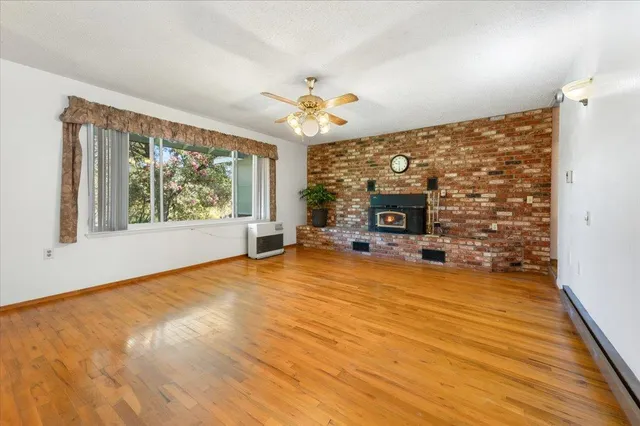 a view of an empty room with window and wooden floor