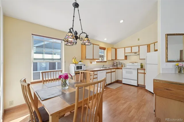 a open dining room with stainless steel appliances kitchen island granite countertop furniture and a chandelier