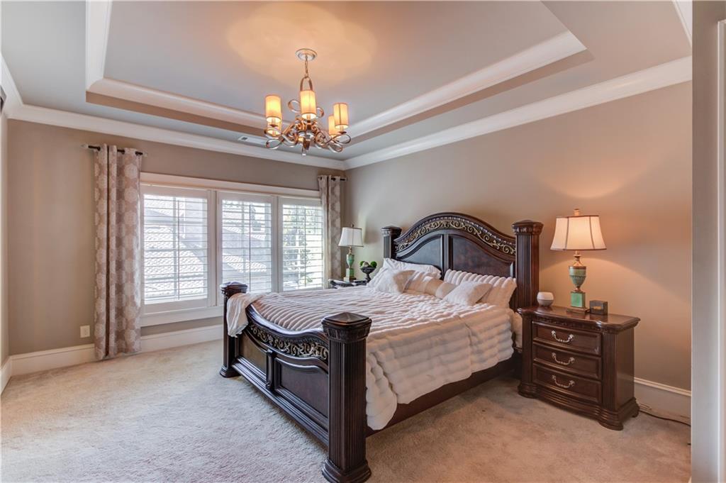 922 Little Darby Lane Suwanee, GA 30024 - Photo 50 of 109 a large bed sitting in a bedroom next to a chandelier and a bookshelf