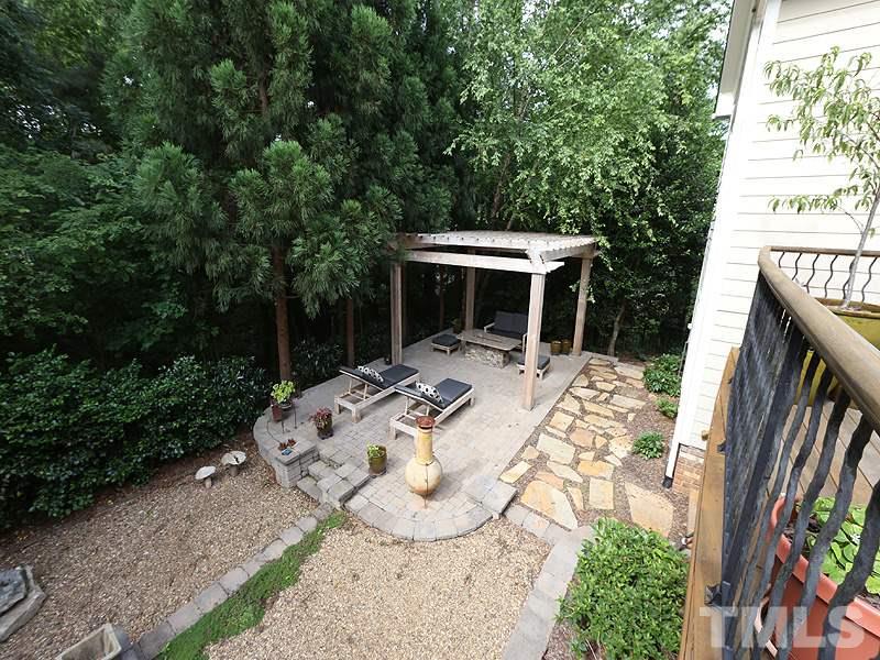 4417 Harbourgate Drive Raleigh, NC 27612 - Photo 24 of 25 Gather with friends and family on the paver patio with pergola above. There is a natural gas fireplace table for cool evenings. Landscape lighting continues throughout the yard highlighting the beautiful trees and shrubs.
