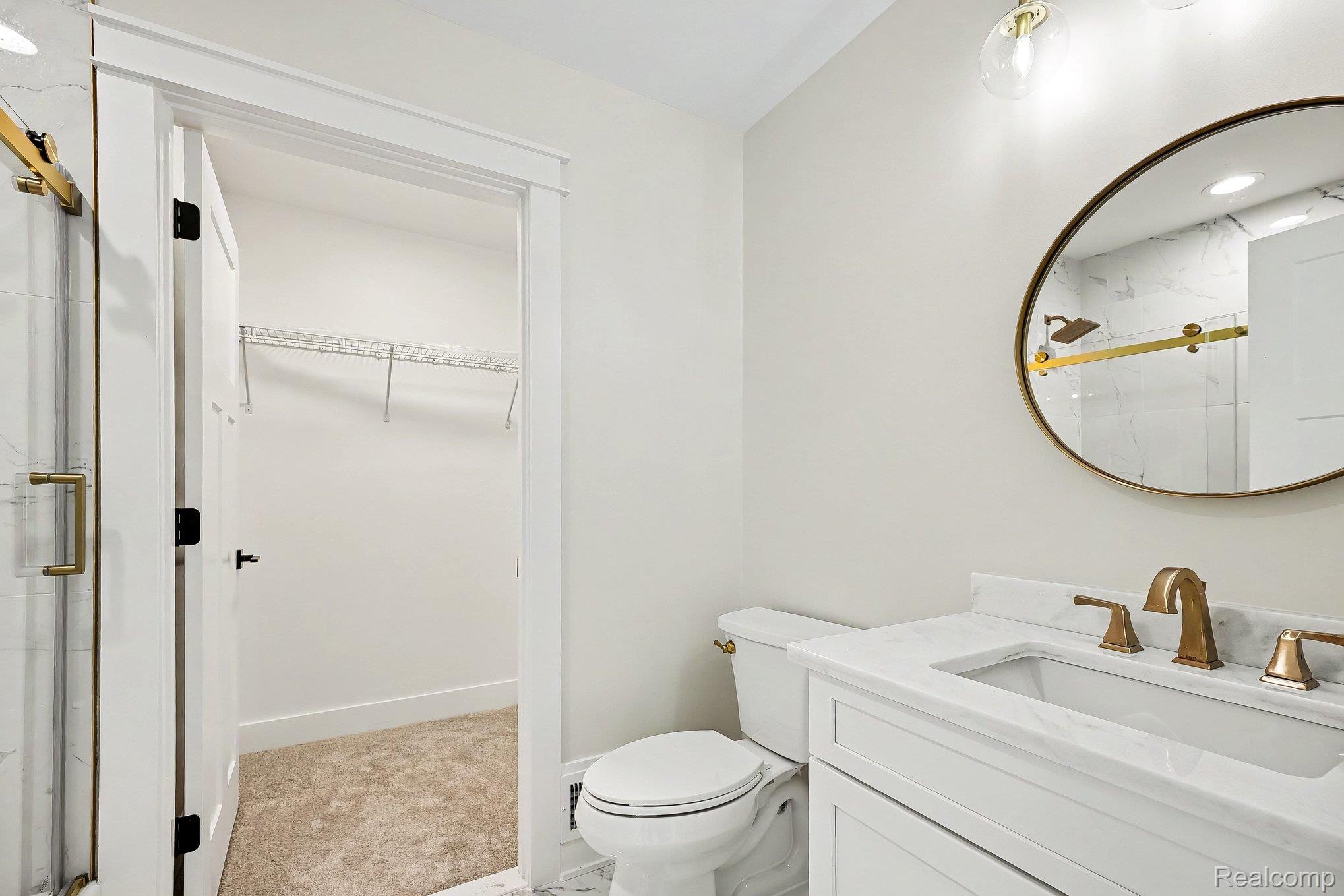 57560 Omo Road Ray, MI 48096 - Photo 33 of 44 Upper level en suite bathroom. Vanity with white cabinetry and integrated sink, gold-finish faucet, and round framed mirror