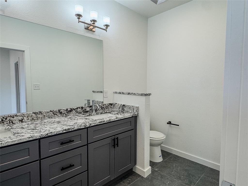 350 Lucy Road Greenville, TX 75402 - Photo 13 of 16 a bathroom with a granite countertop sink a toilet and a mirror