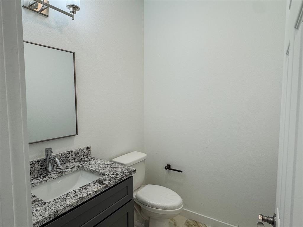 350 Lucy Road Greenville, TX 75402 - Photo 7 of 16 a bathroom with a granite countertop sink a toilet and mirror
