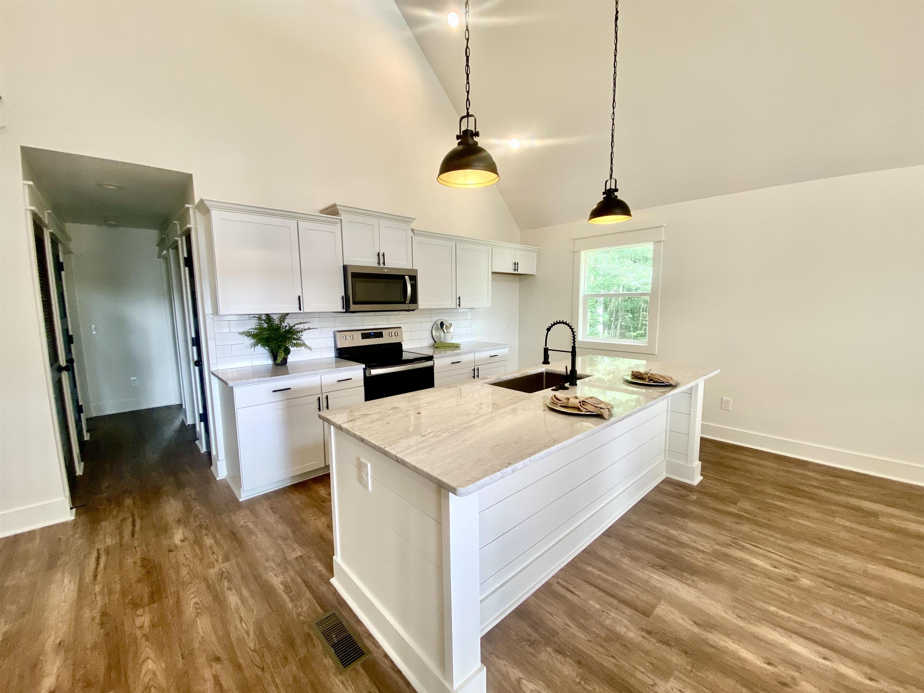 265 Rock Quarry Way Counce, TN 38326 - Photo 6 of 17 a large kitchen with sink a microwave a refrigerator and white cabinets