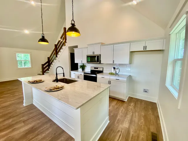 a kitchen that has a lot of cabinets a sink and wooden floor