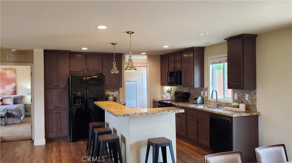 a kitchen with kitchen island granite countertop a sink cabinets and wooden floor